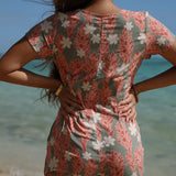 woman with brown hair wearing a jade colored button up romper with tiare ginger print