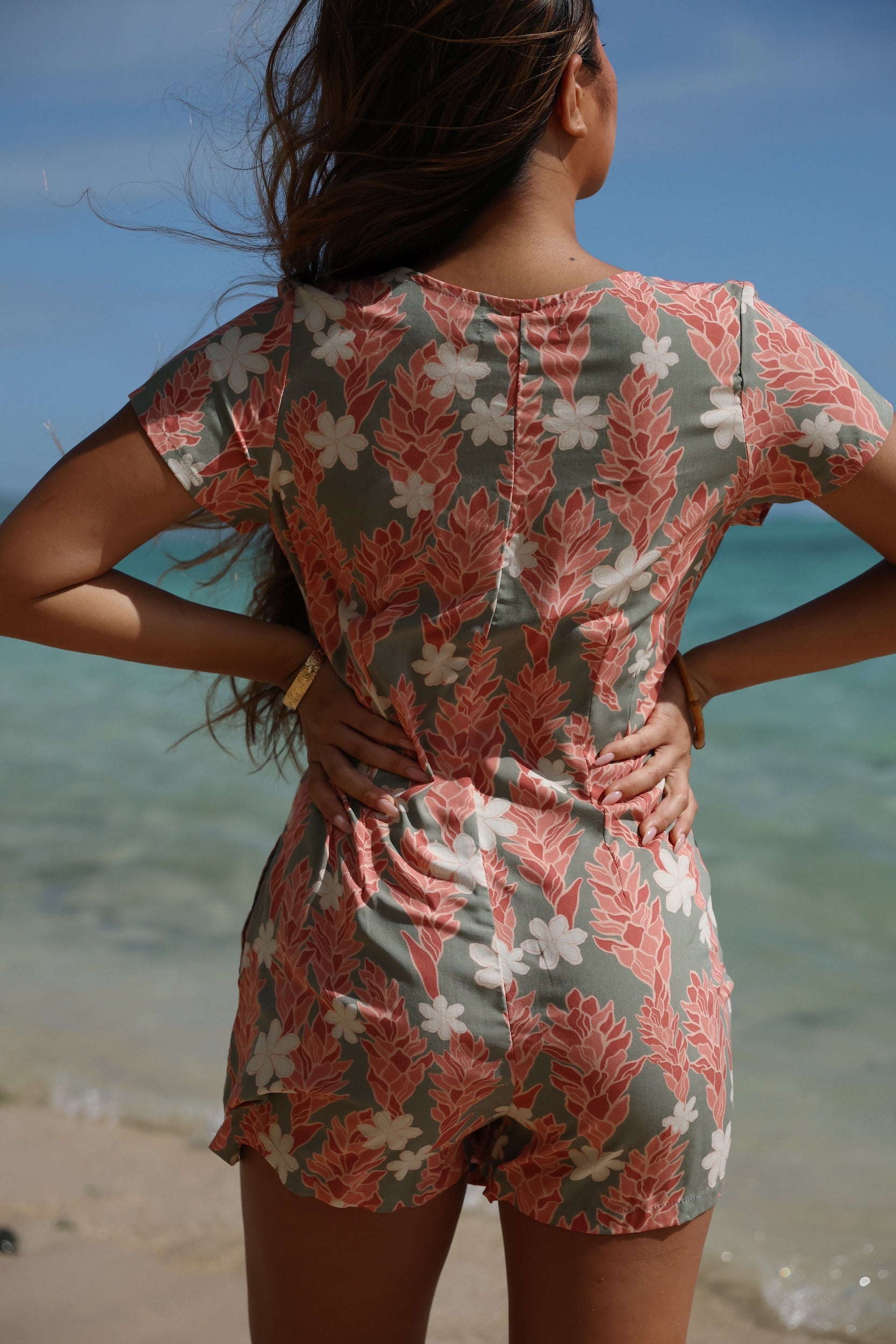 woman with brown hair wearing a jade colored button up romper with tiare ginger print