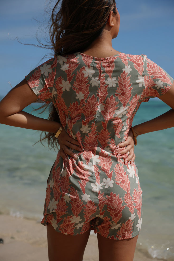 woman with brown hair wearing a jade colored button up romper with tiare ginger print