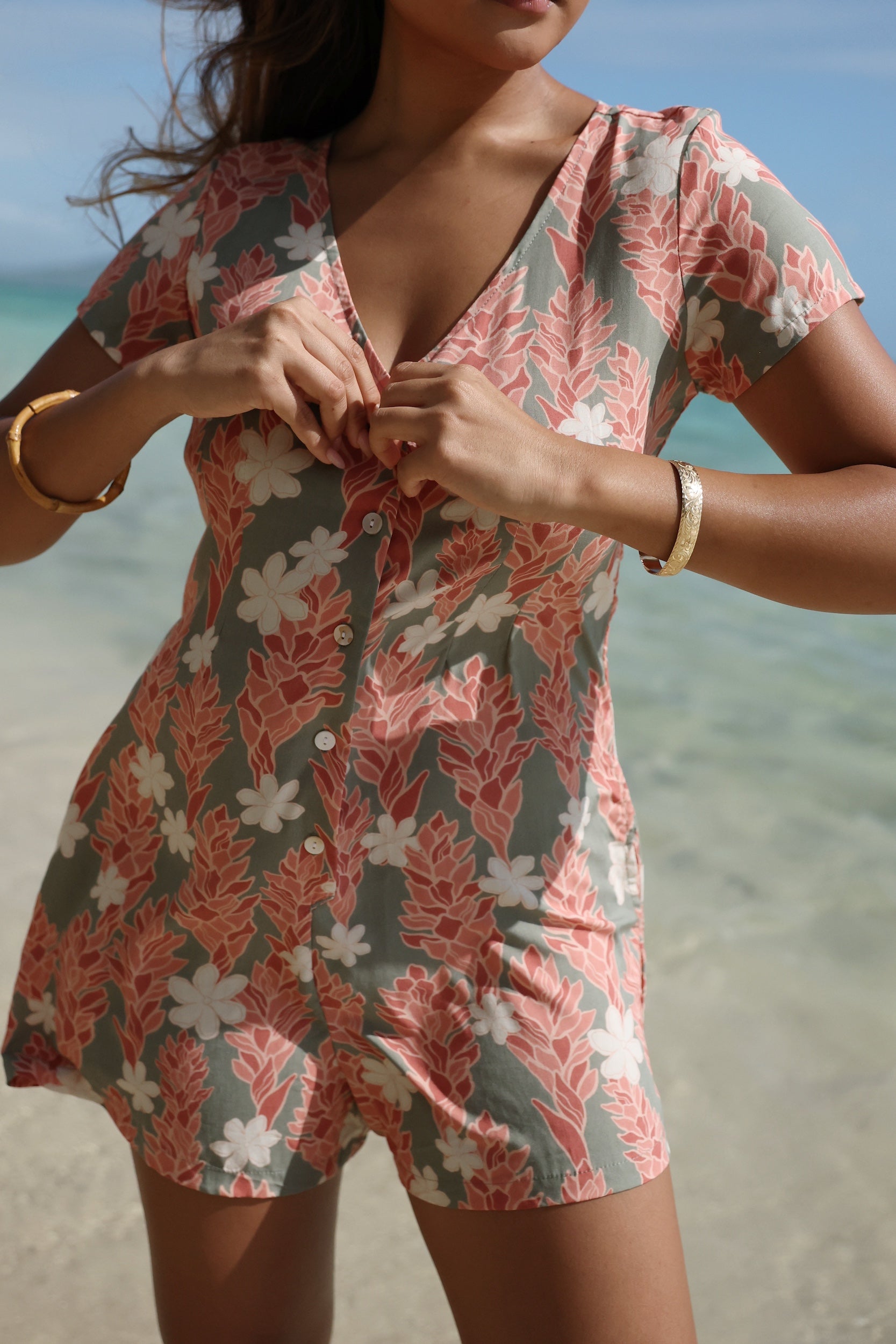 woman with brown hair wearing a jade colored button up romper with tiare ginger print