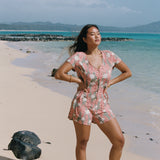 woman with brown hair wearing a jade colored button up romper with tiare ginger print