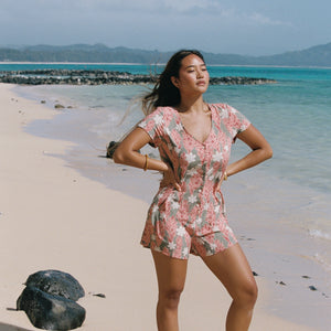 woman with brown hair wearing a jade colored button up romper with tiare ginger print