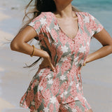 woman with brown hair wearing a jade colored button up romper with tiare ginger print