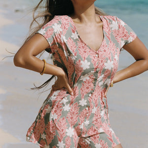 woman with brown hair wearing a jade colored button up romper with tiare ginger print