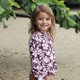 little girl wearing long sleeve one piece bikini in blush and brown hibiscus print.