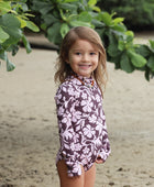 little girl wearing long sleeve one piece bikini in blush and brown hibiscus print.