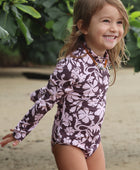 little girl wearing long sleeve one piece bikini in blush and brown hibiscus print.