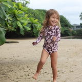 little girl wearing long sleeve one piece bikini in blush and brown hibiscus print.