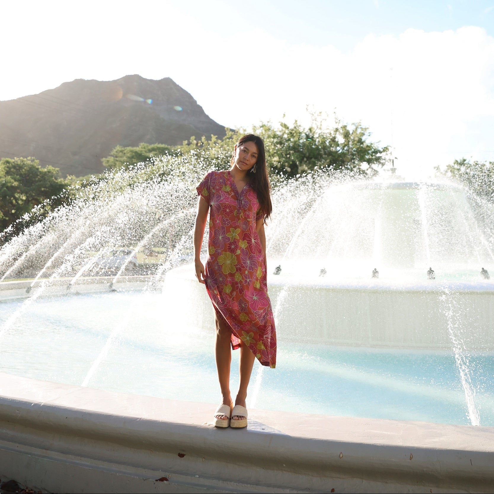 woman wearing terracotta colored v neck maxi dress with large purple and yellow flower print