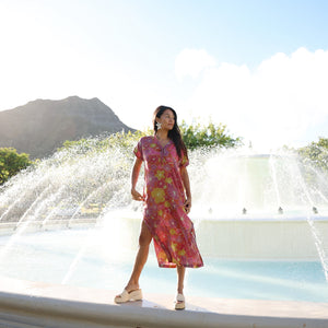 woman wearing terracotta colored v neck maxi dress with large purple and yellow flower print