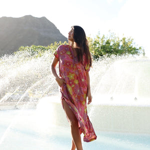 woman wearing terracotta colored v neck maxi dress with large purple and yellow flower print