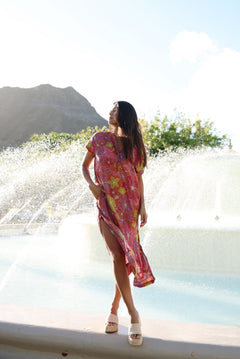 woman wearing terracotta colored v neck maxi dress with large purple and yellow flower print