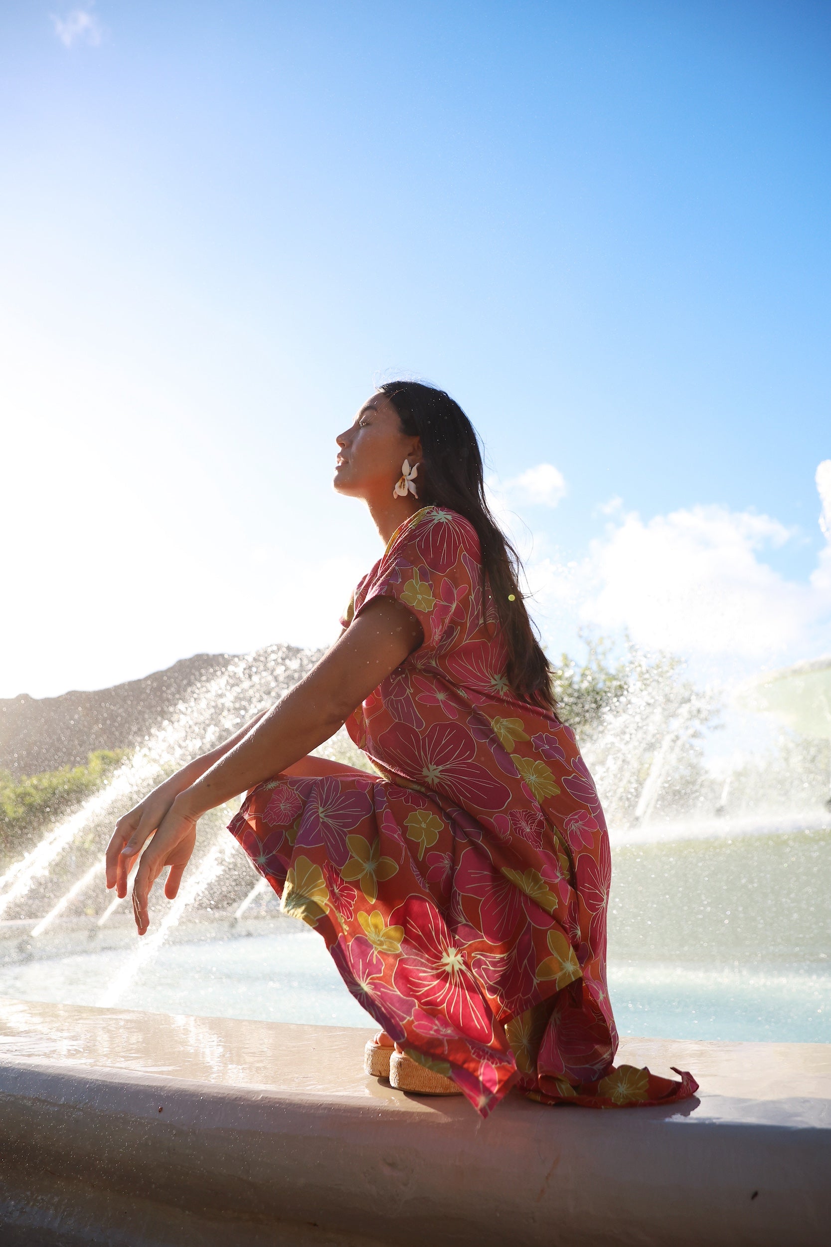 woman wearing terracotta colored v neck maxi dress with large purple and yellow flower print