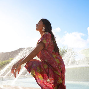 woman wearing terracotta colored v neck maxi dress with large purple and yellow flower print