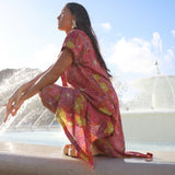 woman wearing terracotta colored v neck maxi dress with large purple and yellow flower print