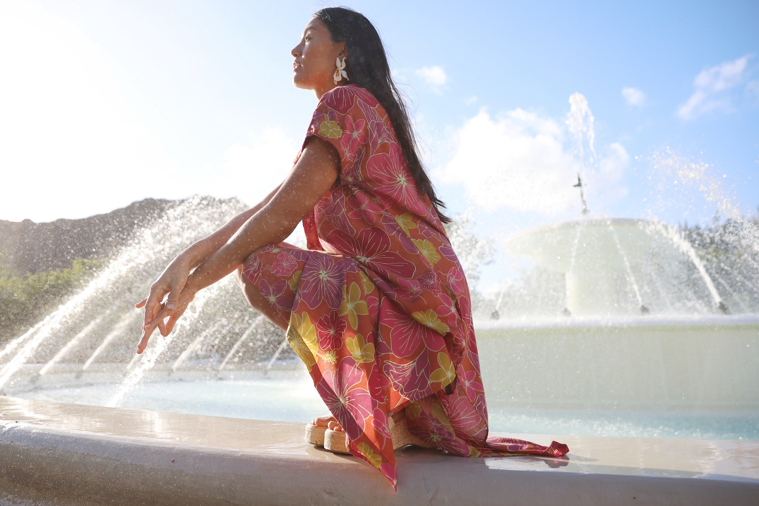 woman wearing terracotta colored v neck maxi dress with large purple and yellow flower print