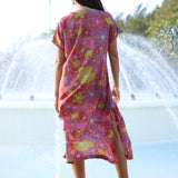woman wearing terracotta colored v neck maxi dress with large purple and yellow flower print