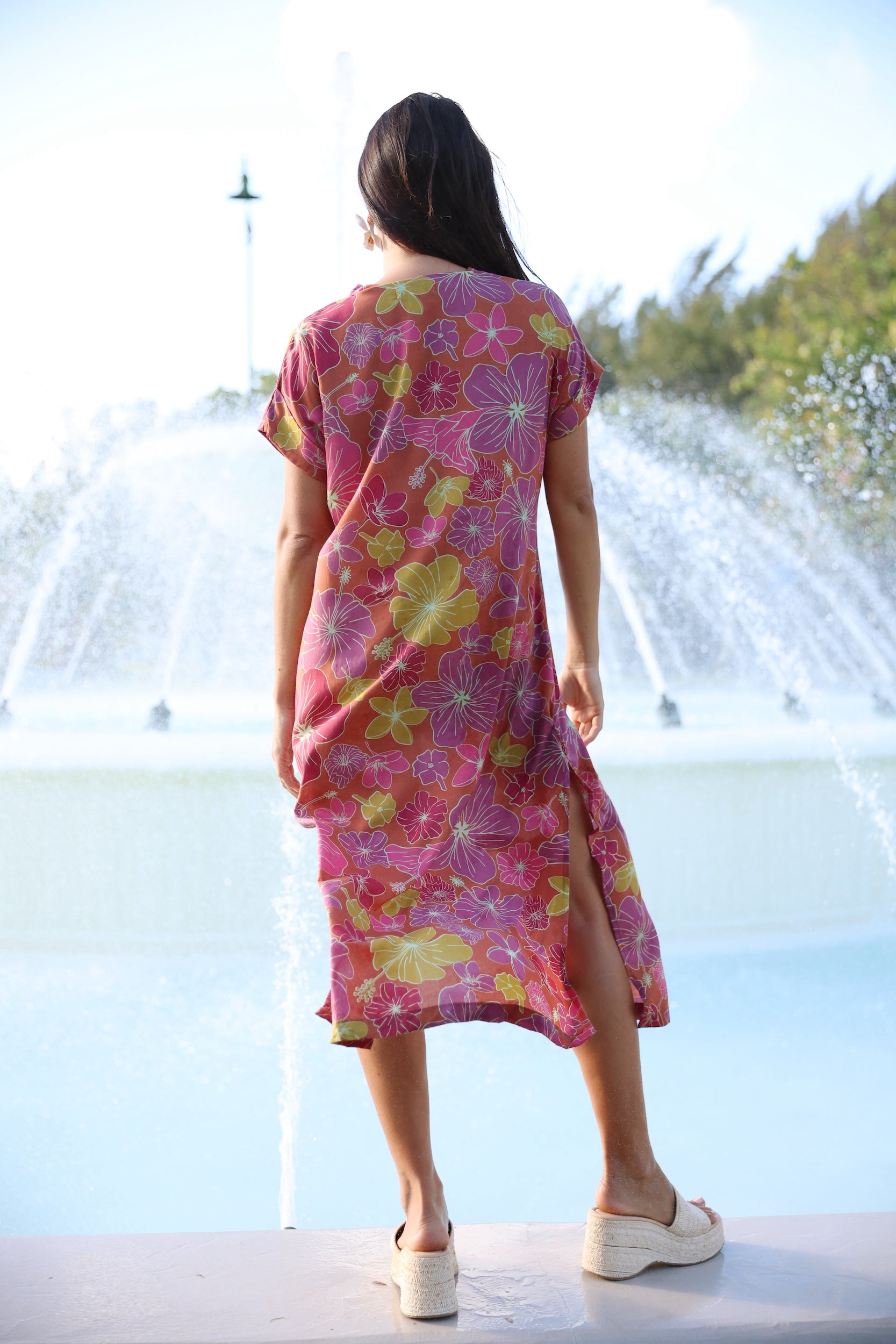 woman wearing terracotta colored v neck maxi dress with large purple and yellow flower print