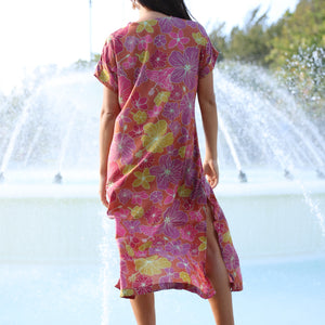 woman wearing terracotta colored v neck maxi dress with large purple and yellow flower print
