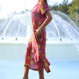 woman wearing terracotta colored v neck maxi dress with large purple and yellow flower print