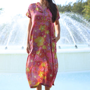 woman wearing terracotta colored v neck maxi dress with large purple and yellow flower print