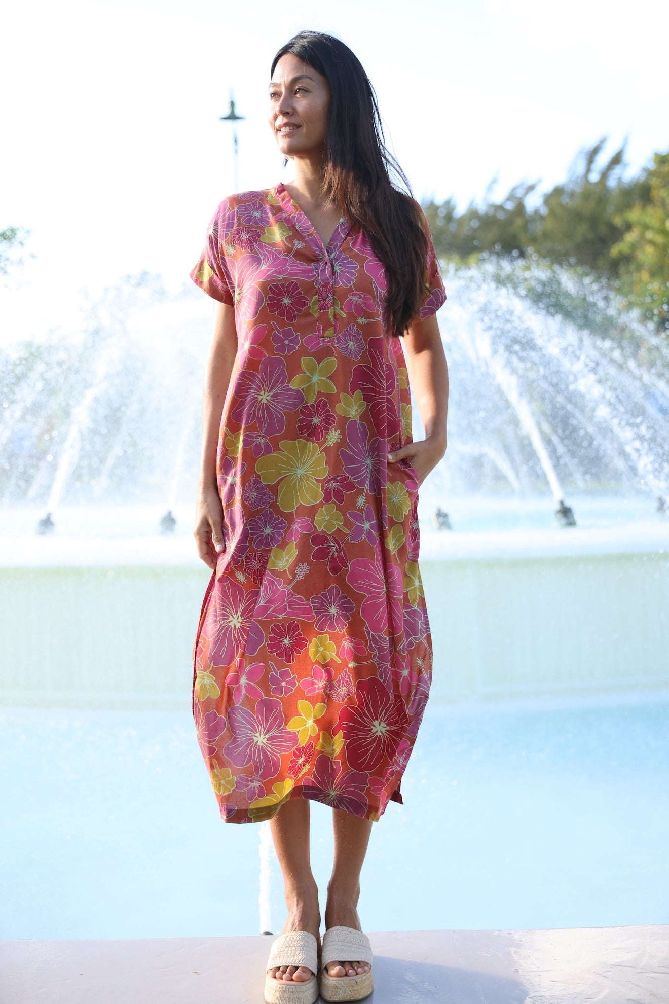 woman wearing terracotta colored v neck maxi dress with large purple and yellow flower print