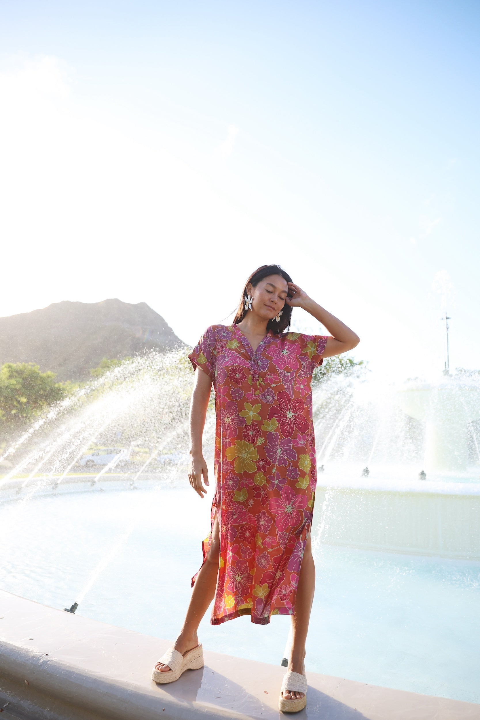 woman wearing terracotta colored v neck maxi dress with large purple and yellow flower print