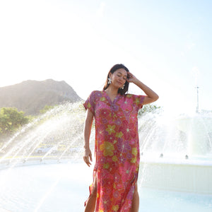 woman wearing terracotta colored v neck maxi dress with large purple and yellow flower print