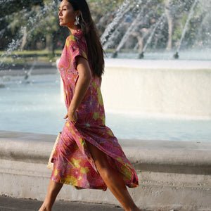 woman wearing terracotta colored v neck maxi dress with large purple and yellow flower print