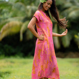 woman wearing a pink v neck maxi dress with lei print