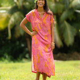 woman wearing a pink v neck maxi dress with lei print