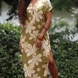 woman with brown hair wearing a maxi dress in a green color with naupaka pattern throughout. 