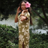 woman with brown hair wearing a maxi dress in a green color with naupaka pattern throughout. 
