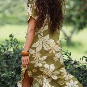 woman with brown hair wearing a maxi dress in a green color with naupaka pattern throughout. 