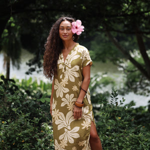 woman with brown hair wearing a maxi dress in a green color with naupaka pattern throughout. 