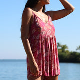 woman with brown hair wearing saghetti strap romper with shell and pua print in a pink color