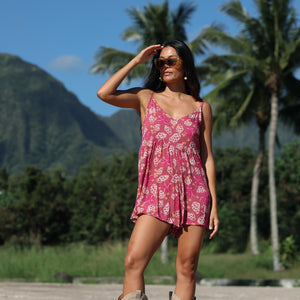 woman with brown hair wearing saghetti strap romper with shell and pua print in a pink color