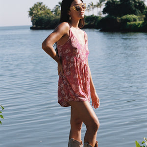 woman with brown hair wearing saghetti strap romper with shell and pua print in a pink color