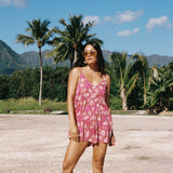 woman with brown hair wearing saghetti strap romper with shell and pua print in a pink color