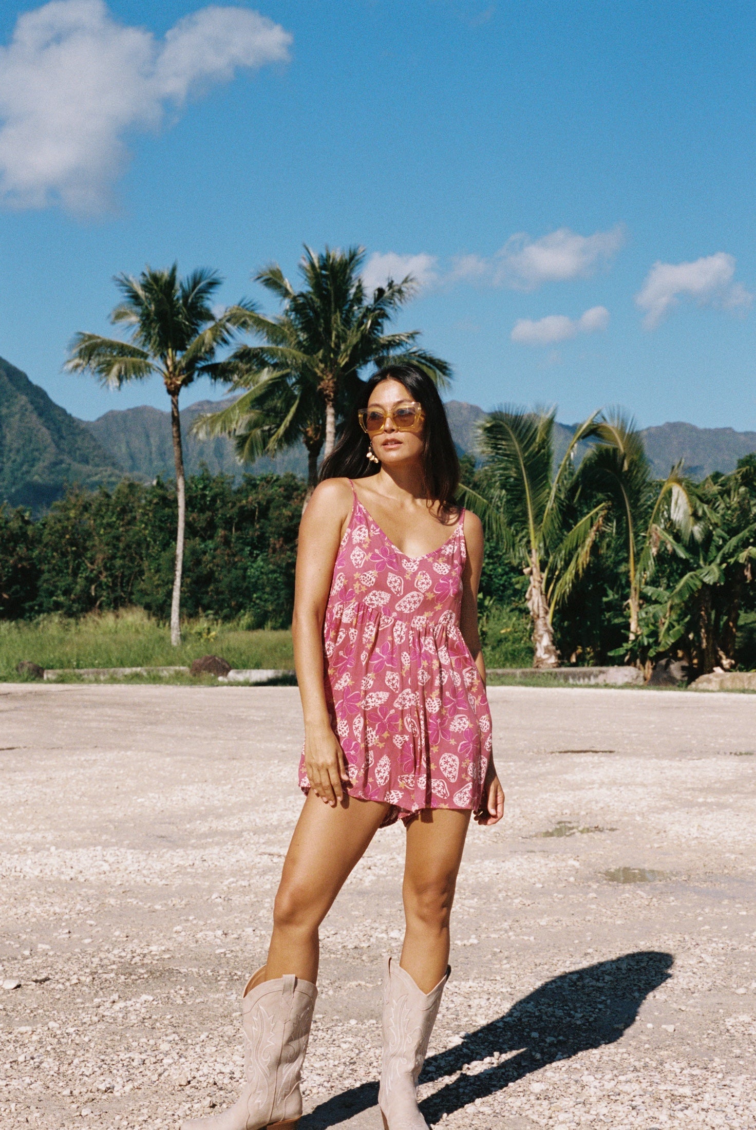 woman with brown hair wearing saghetti strap romper with shell and pua print in a pink color