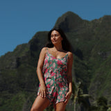 woman with brown hair wearing a spaghetti strap romper with shell and pua print in a teal color