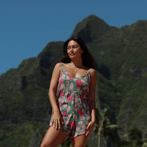woman with brown hair wearing a spaghetti strap romper with shell and pua print in a teal color