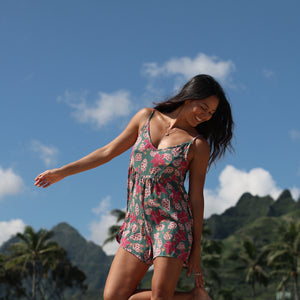 woman with brown hair wearing a spghetti strap romper with shell and pua print in a teal color