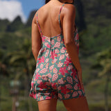 woman with brown hair wearing a spghetti strap romper with shell and pua print in a teal color