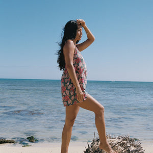 woman with brown hair wearing a spghetti strap romper with shell and pua print in a teal color