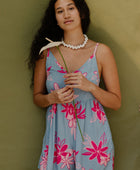 Woman in short sleeveless romper with pink floral print on light blue ground.