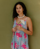 Woman in short sleeveless romper with pink floral print on light blue ground.