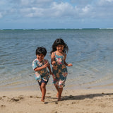 little boy wearing a teal aloha shirt with cream colored orchid blossom pattern