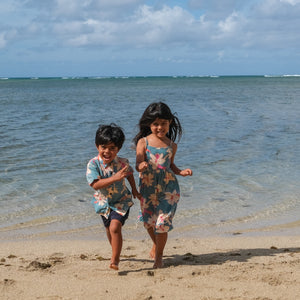 little boy wearing a teal aloha shirt with cream colored orchid blossom pattern