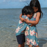 little boy wearing a teal aloha shirt with cream colored orchid blossom pattern